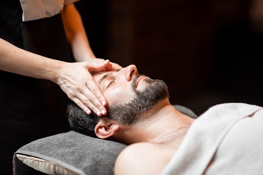 Therapist performing a facial massage during a men’s skincare ritual