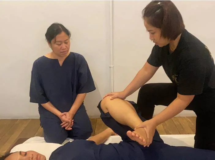 Instructor correcting body position during massage training